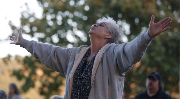 A woman prays during an October 3 candlelight vigil for victims of the Umpqua Community College shooting in Winston, Oregon. The gunman who killed his English professor and eight others at the Oregon community college committed suicide after a shootout with police who were on the scene within five minutes and exchanged fire with him almost immediately, authorities said.